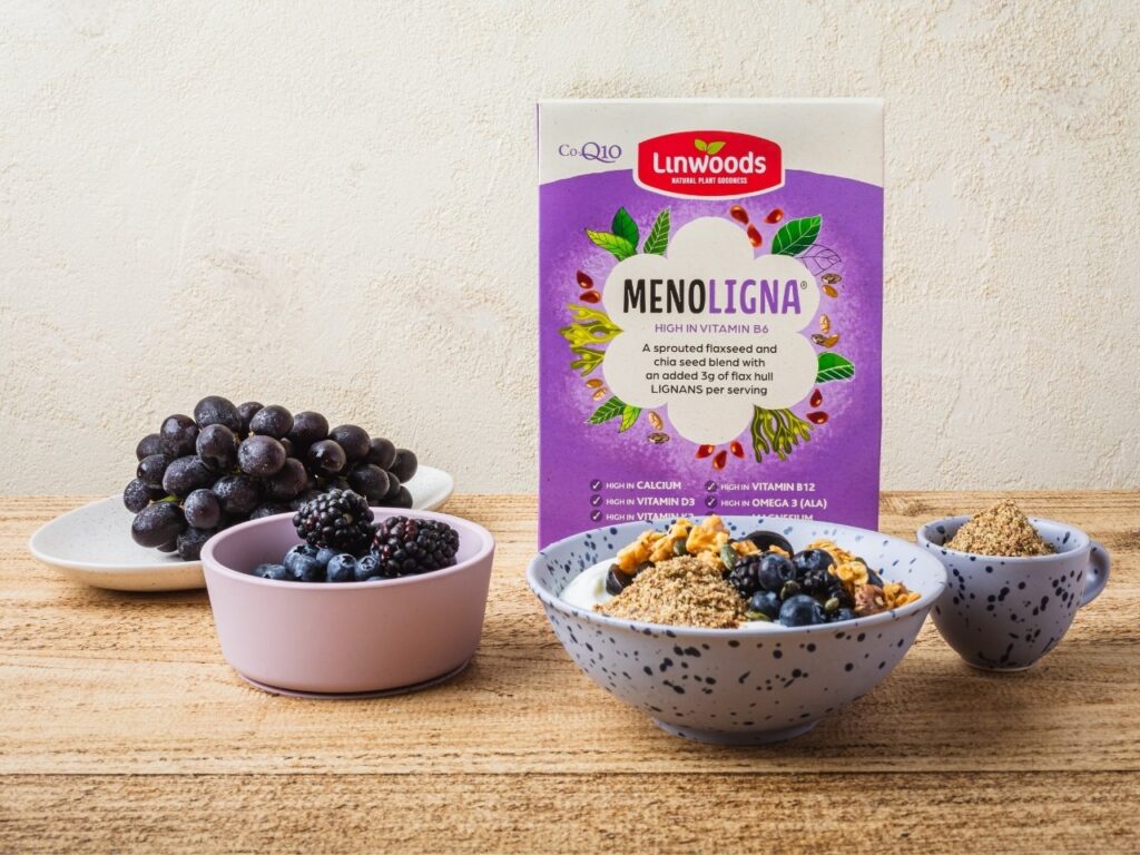 Linwoods Menoligna flaxseed and chia seed blend displayed with yoghurt, berries, grapes and granola – a nutrient-rich source of phytoestrogens, fibre, omega-3s and bone-supportive nutrients to complement a perimenopause diet.