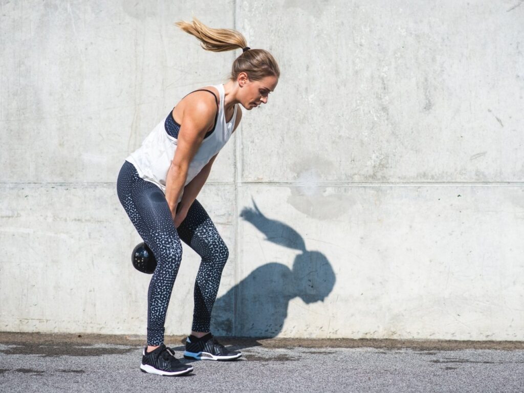 Woman doing kettlebell swings outdoors, a powerful strength-training exercise to support hormone balance and bone health in perimenopause.