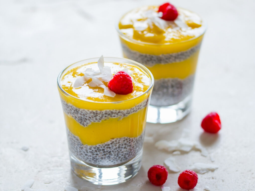 Tropical chia pudding layered with mango purée and topped with raspberries and coconut flakes – a fibre-rich, hormone-supportive treat for your perimenopause diet.