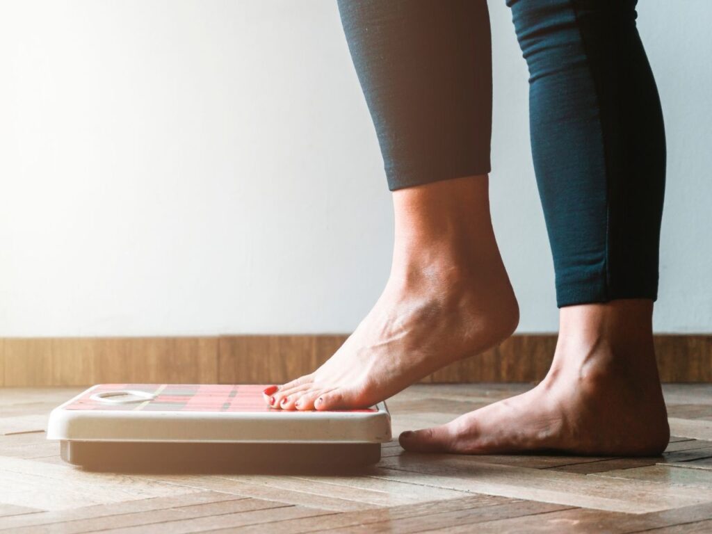 Close up of a women's feet and legs as she is about to step on the scale, representing weight gain in perimenopause.